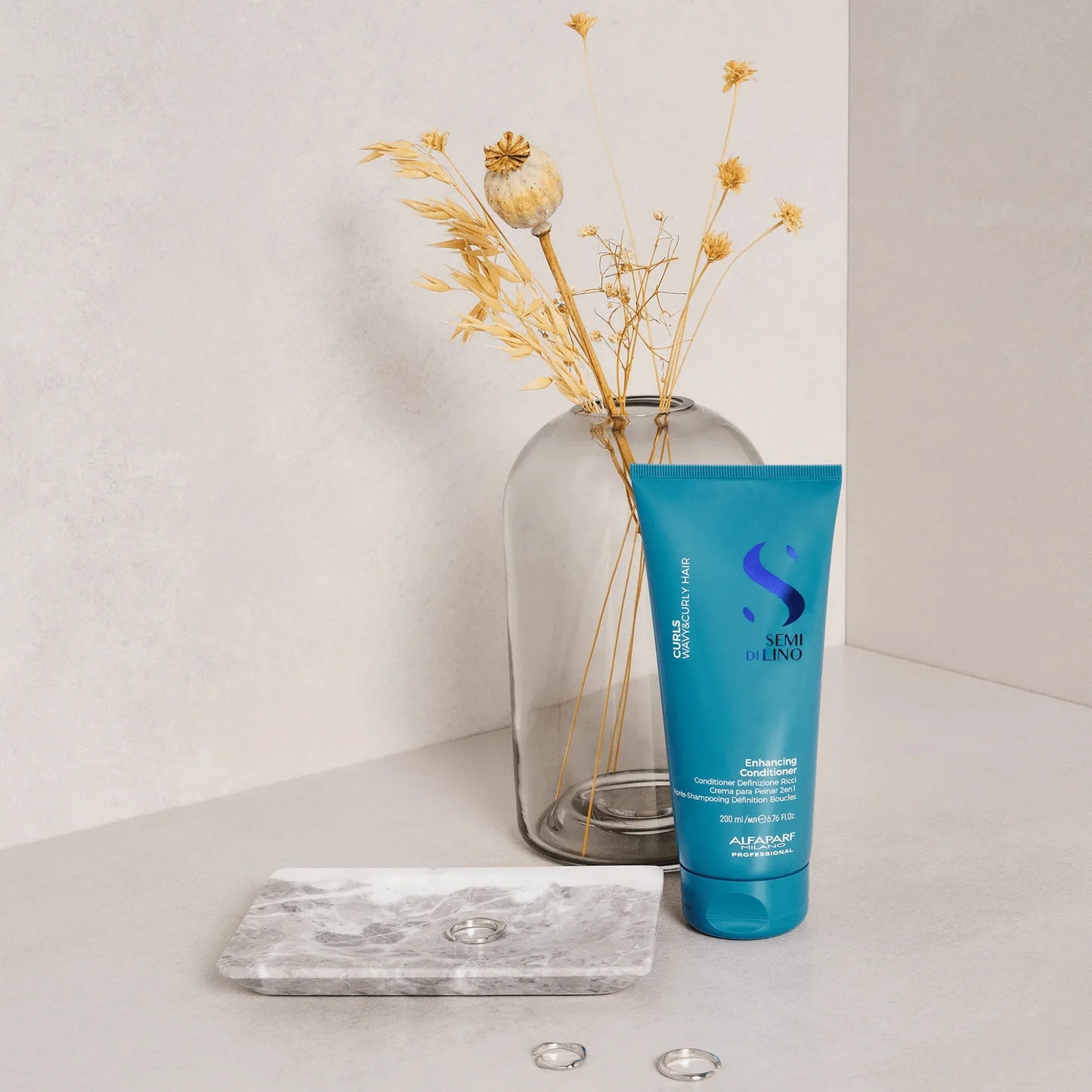 Alfaparf Semi di Lino curl enhancing conditioner 200ml tube beside dried flowers and jewelry dish.