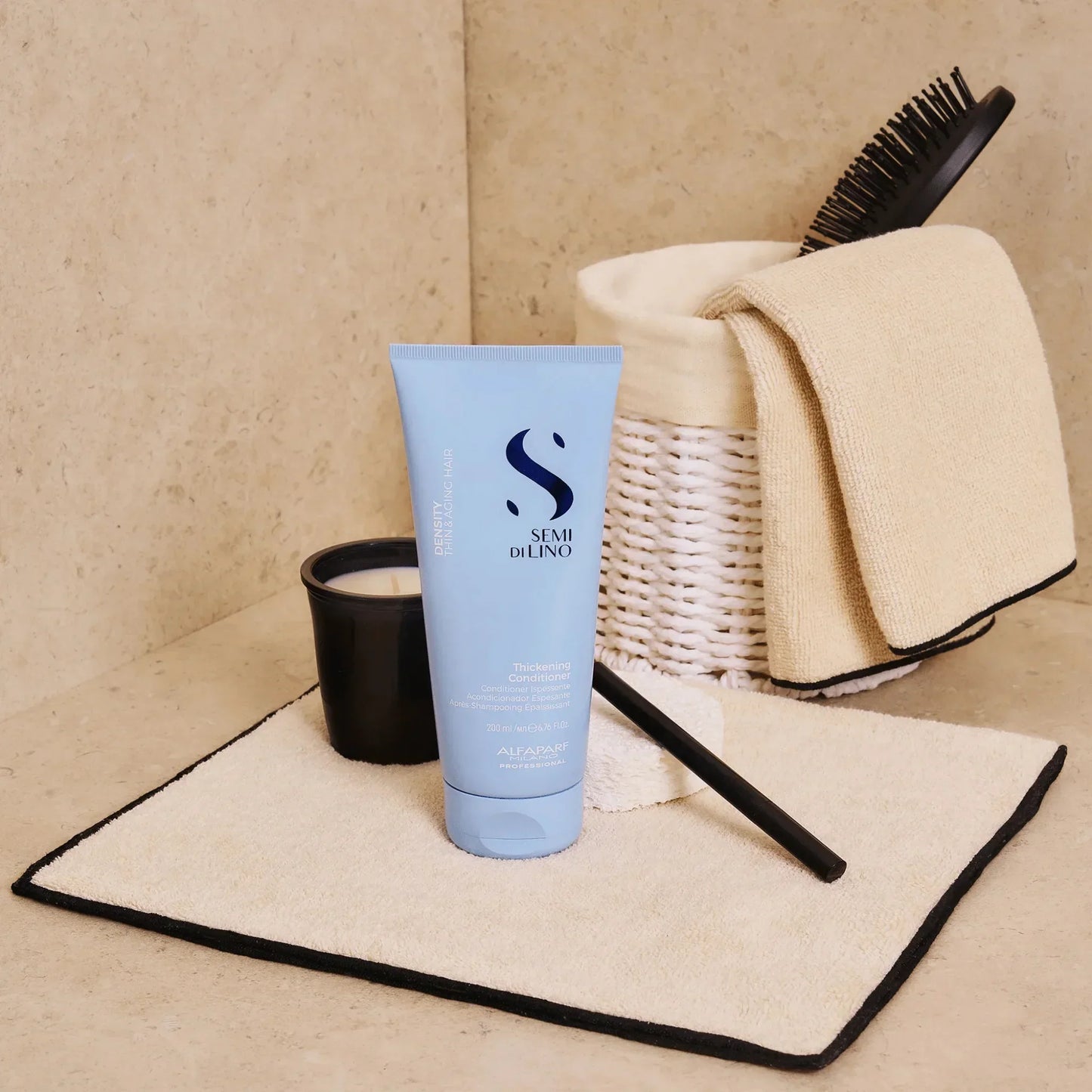 Alfaparf Semi Di Lino thickening conditioner tube on towel with hairbrush and candle