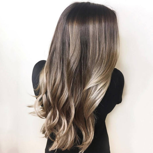 Long wavy hair with natural blonde balayage highlights against a plain background